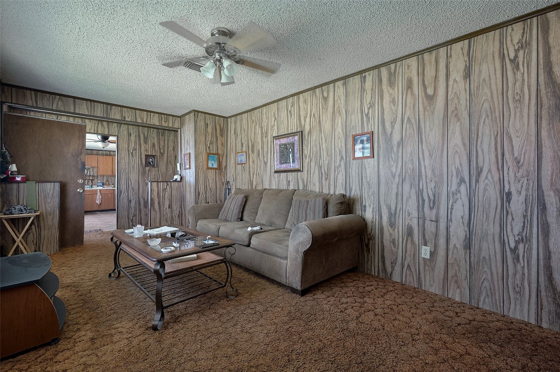 16128 1/2 Ridlon Street Channelview, TX 77530 - Photo 31 of 43 Inside the second house, the living room feels cozy with wood-toned paneling, soft carpeting underfoot, and a ceiling fan.