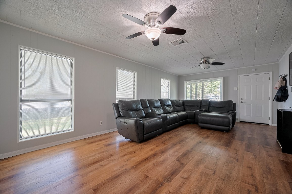 16128 1/2 Ridlon Street Channelview, TX 77530 - Photo 9 of 43 In the living area, oversized windows flood the room with natural light and two ceiling fans enhance comfort. Wood-style floors bring warmth to this generous space.