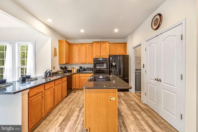 a kitchen with stainless steel appliances granite countertop a refrigerator a stove top oven and a dining table with wooden floor