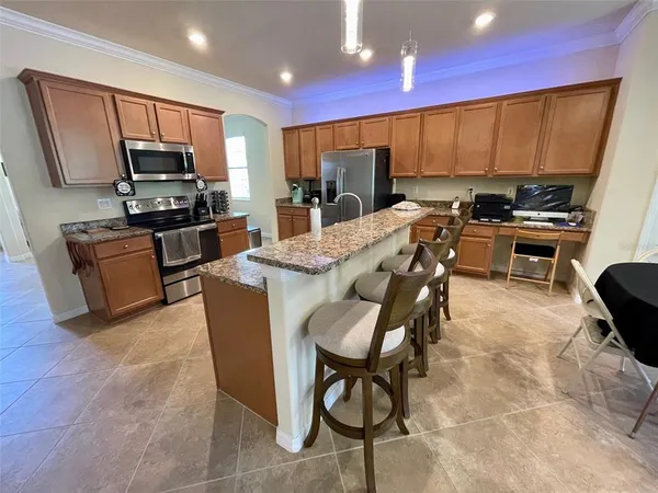 a kitchen with stainless steel appliances granite countertop a stove top oven a sink dishwasher a dining table and chairs with wooden floor