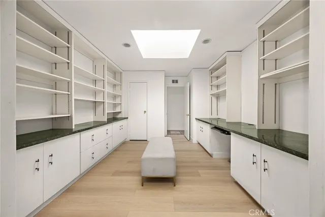 a large white kitchen with granite countertop a sink and dishwasher with white cabinets