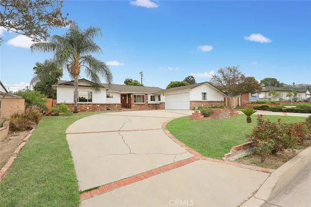 a front view of a house with a yard and potted plants