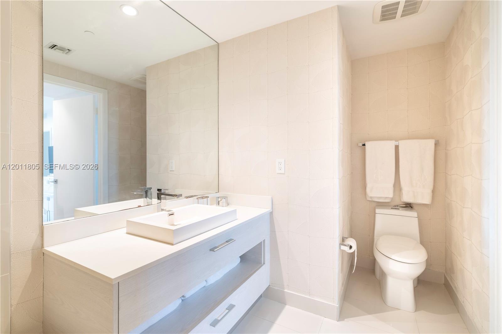 55 Southwest 9th Street, Unit 3404 Miami, FL 33130 - Photo 14 of 25 a bathroom with a sink a toilet and a large mirror