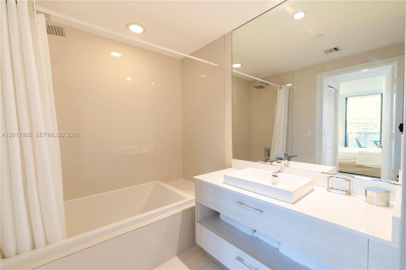 55 Southwest 9th Street, Unit 3404 Miami, FL 33130 - Photo 15 of 25 a bathroom with a tub sink and mirror