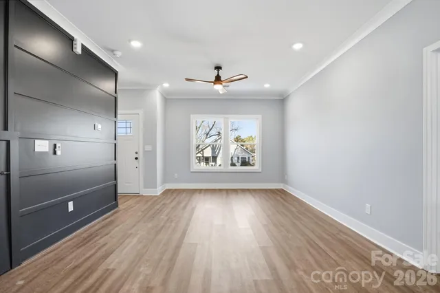 a view of an empty room with wooden floor and a window