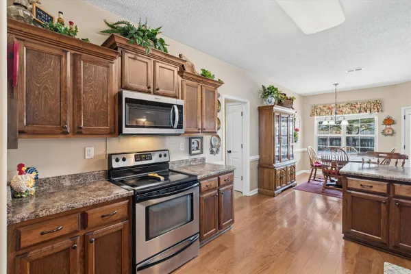 a kitchen with stainless steel appliances granite countertop a stove a sink dishwasher and a microwave oven with wooden floor
