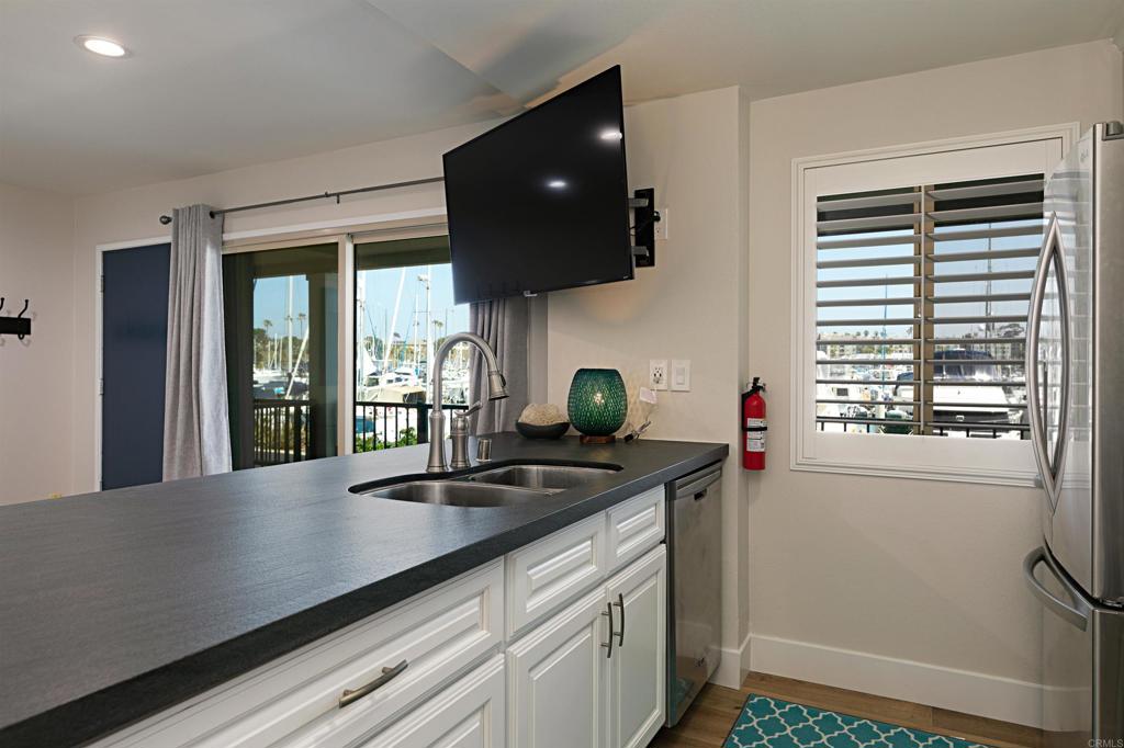 1202 North Pacific Street, Unit 106B Oceanside, CA 92054 - Photo 11 of 18 a kitchen with stainless steel appliances a sink a stove and a wooden floor