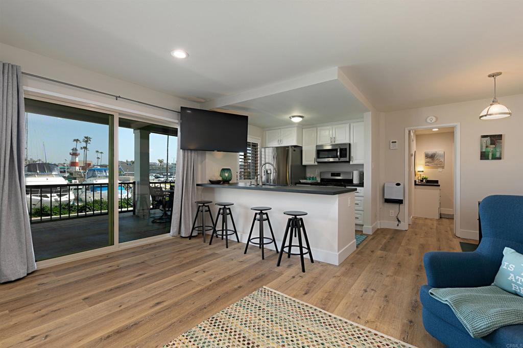 1202 North Pacific Street, Unit 106B Oceanside, CA 92054 - Photo 8 of 18 a kitchen with stainless steel appliances kitchen island granite countertop a refrigerator a stove top oven a sink with island and chairs