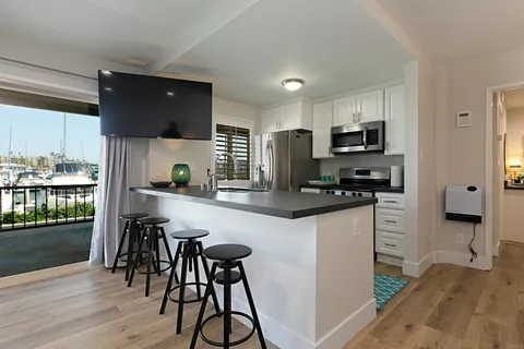 a kitchen with stainless steel appliances a microwave a refrigerator a stove a sink and white cabinets with wooden floor