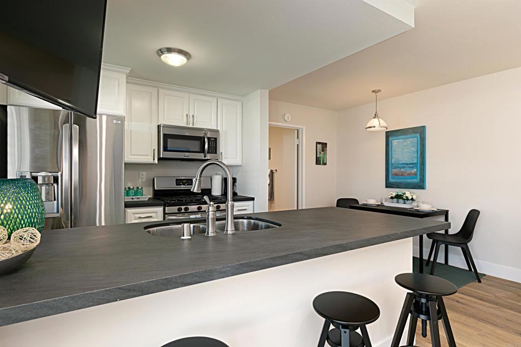 1202 North Pacific Street, Unit 106B Oceanside, CA 92054 - Photo 10 of 18 a kitchen with a table chairs and refrigerator