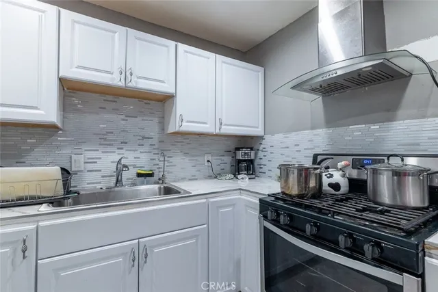 a kitchen with stainless steel appliances granite countertop white cabinets and a stove top oven