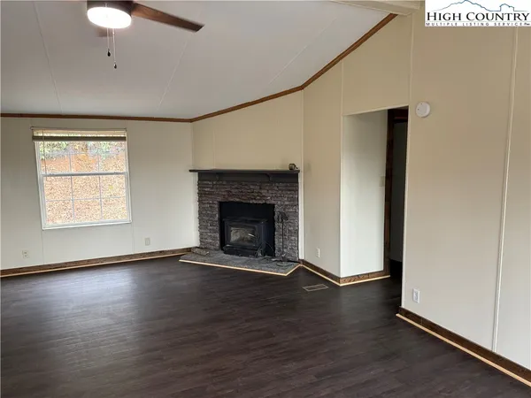 an empty room with wooden floor a fireplace and windows
