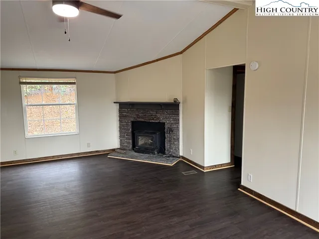 an empty room with wooden floor a fireplace and windows