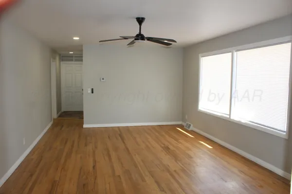 a view of an empty room with wooden floor and a window