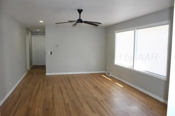 a view of an empty room with a window and wooden floor