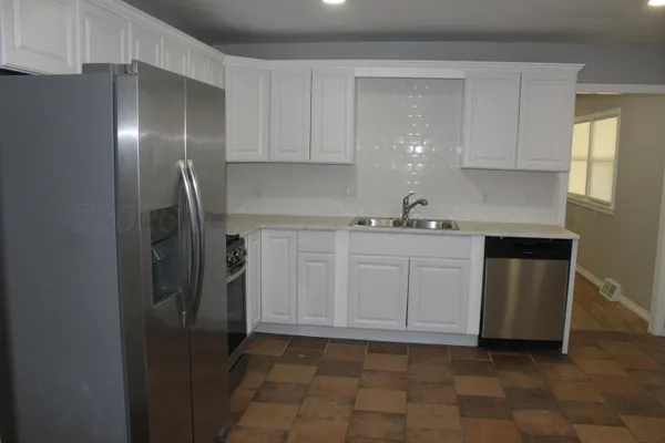 a kitchen with a sink a refrigerator and cabinets