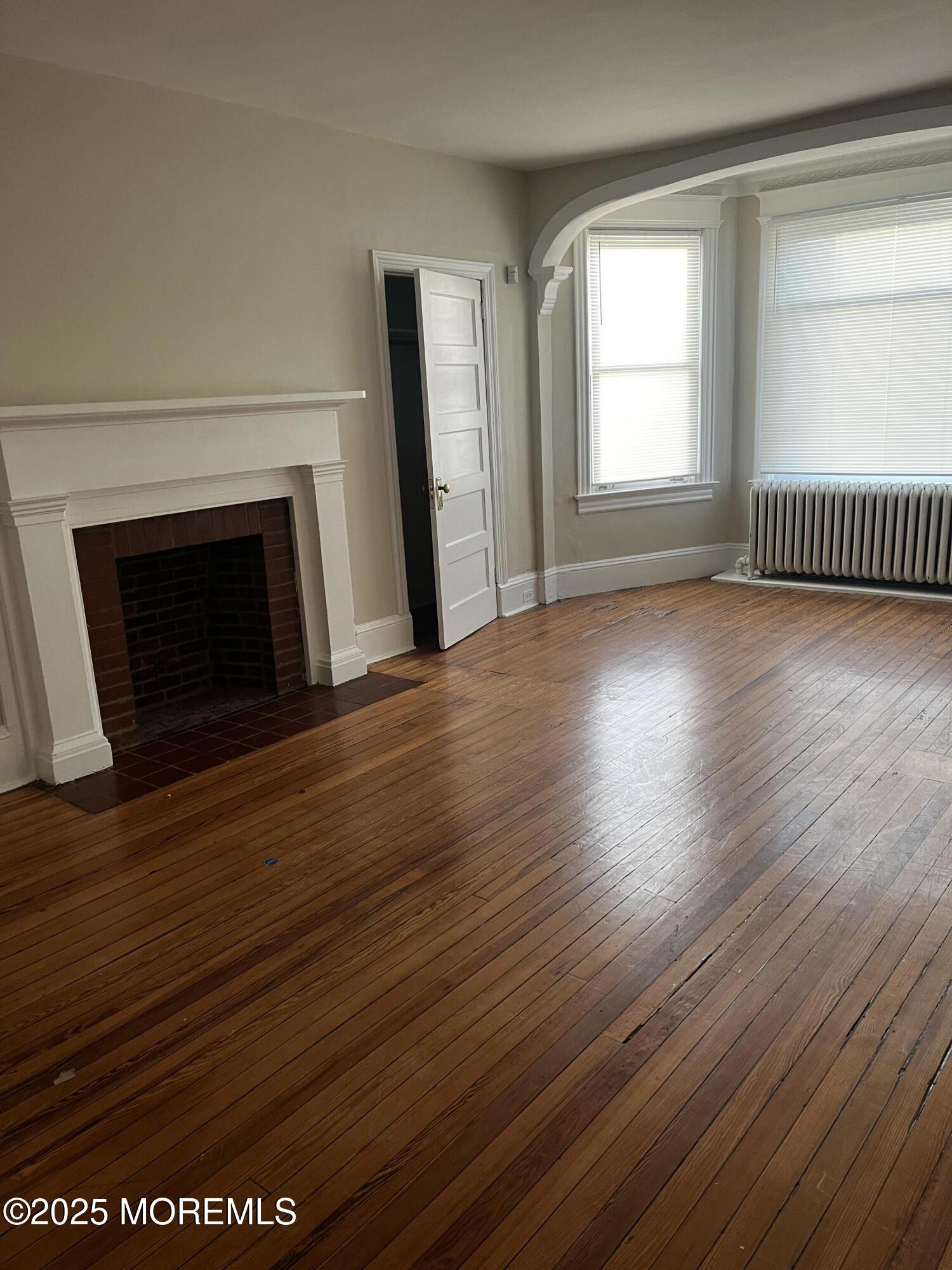 103 Main Street, Unit 1 Matawan, NJ 07747 - Photo 1 of 12 an empty room with wooden floor fireplace and windows