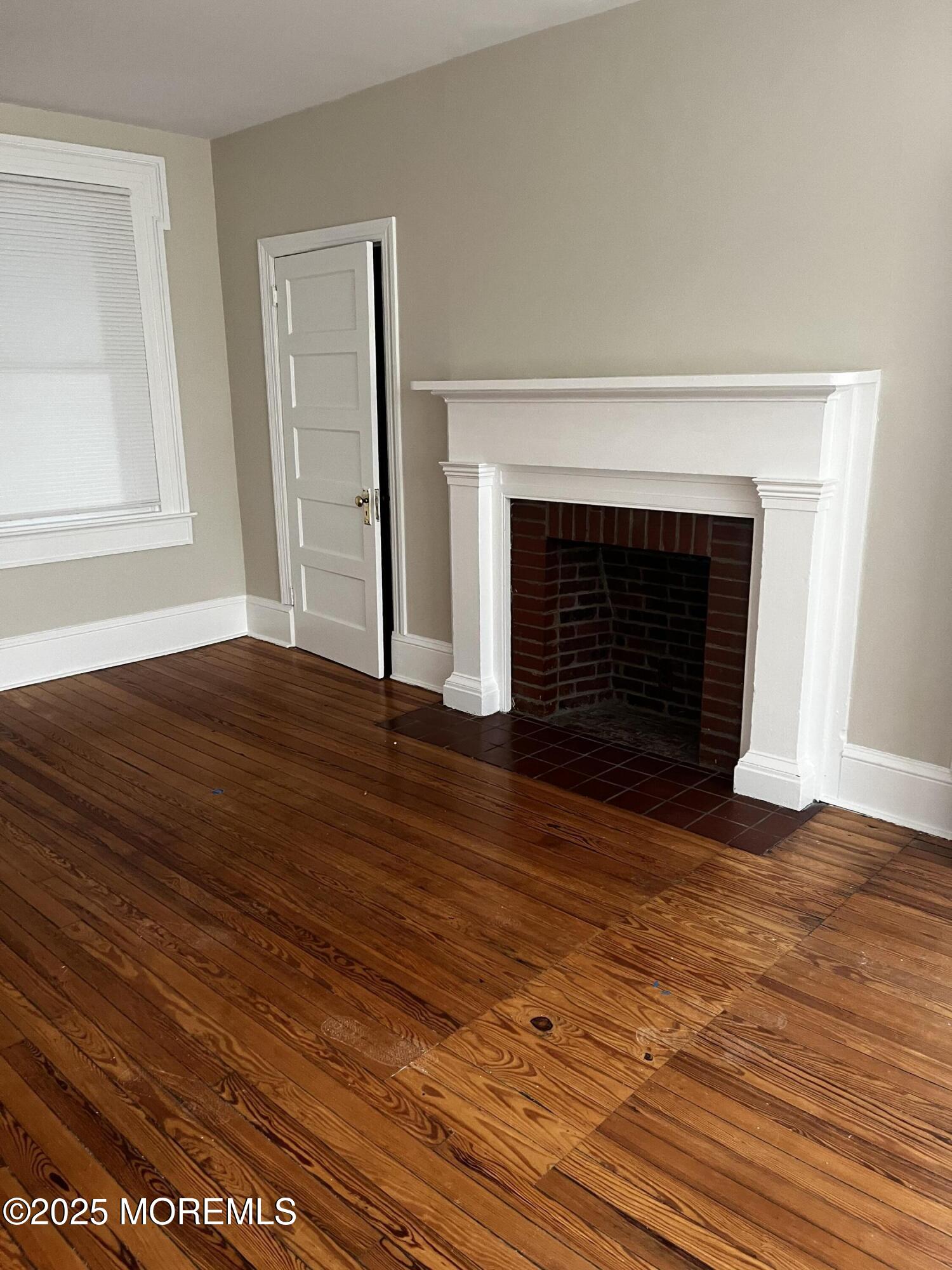 103 Main Street, Unit 1 Matawan, NJ 07747 - Photo 2 of 12 a view of an empty room with wooden floor fireplace and a window
