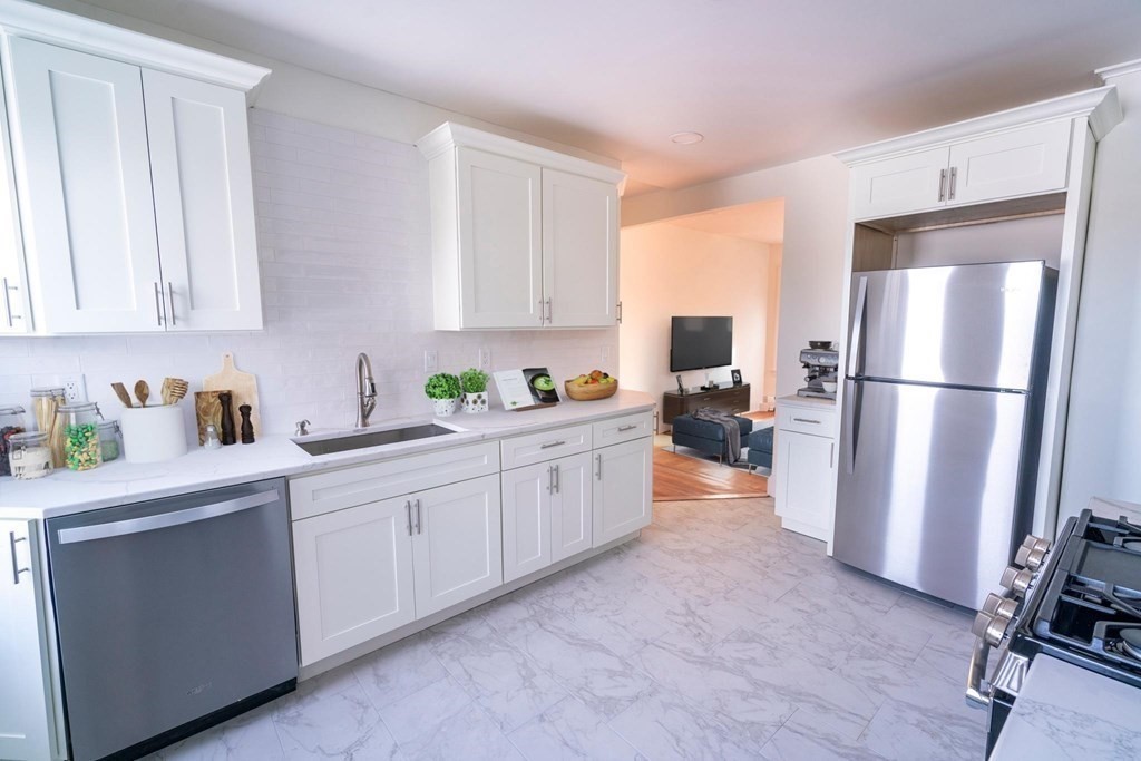 a kitchen with a refrigerator a stove a sink and white cabinets