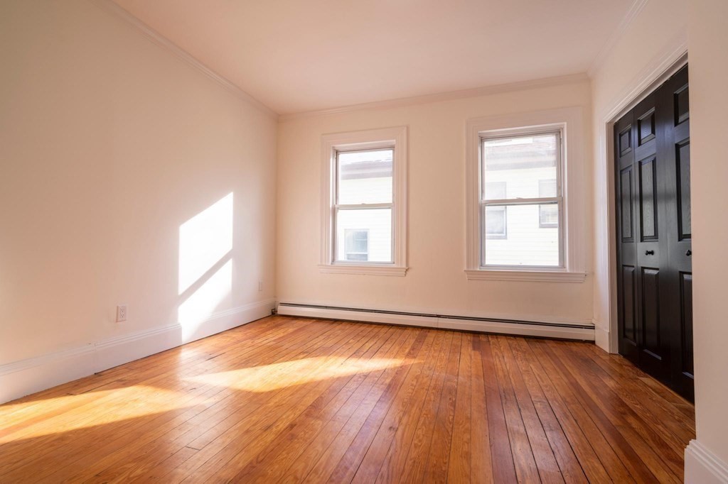 302 Summit Avenue, Unit 1 Boston, MA 02135 - Photo 6 of 13 an empty room with wooden floor and windows