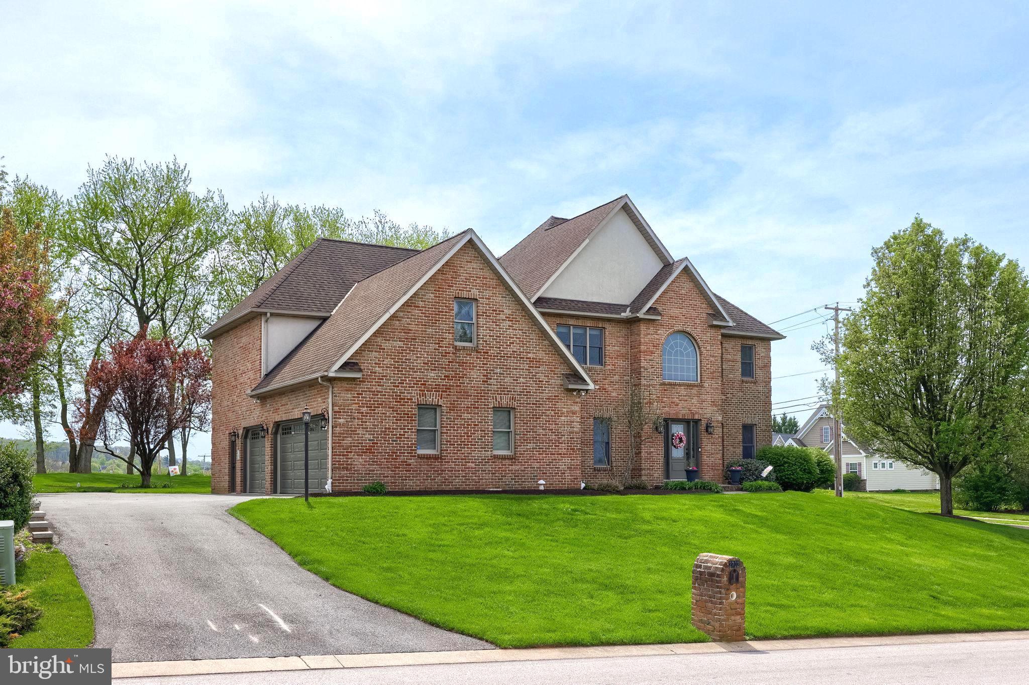 a view of a big house with a big yard and large trees