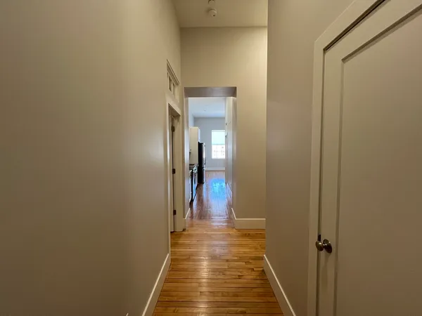 a view of a hallway with wooden floor and a bathroom