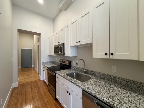 a kitchen with granite countertop a sink a stove and cabinets