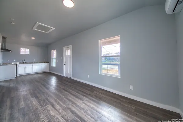 a view of an empty room with window and wooden floor