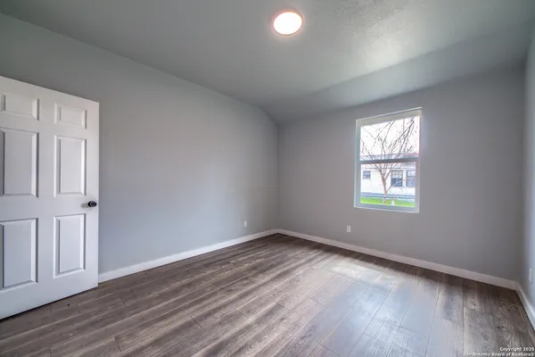 an empty room with wooden floor and windows