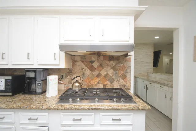 a kitchen with granite countertop cabinets stainless steel appliances a sink and a window
