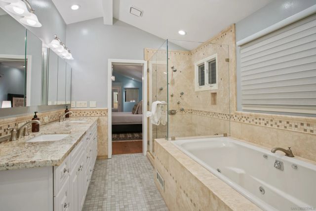 a spacious bathroom with a bathtub double sink shower and mirror
