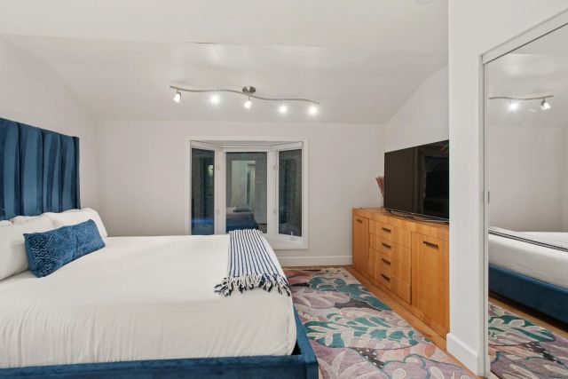 a spacious bedroom with a bed and a flat screen tv