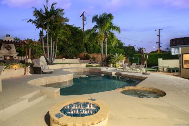 a view of a swimming pool with a bench and palm trees