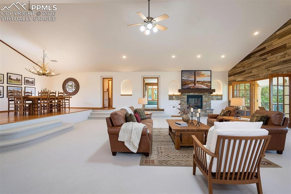 2550 Slocum Road Peyton, CO 80831 - Photo 8 of 50 virtually staged Vaulted ceiling living area featuring a stone fireplace with wood mantel, wood accent wall, and recessed lighting
