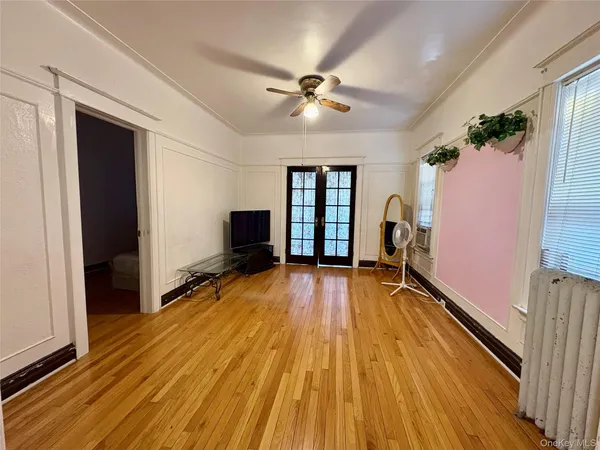 a view of empty room with wooden floor and fan