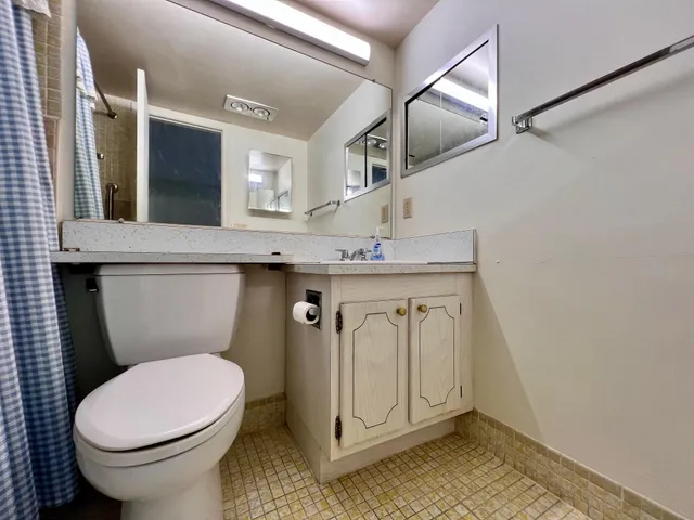 a bathroom with a granite countertop toilet sink and mirror
