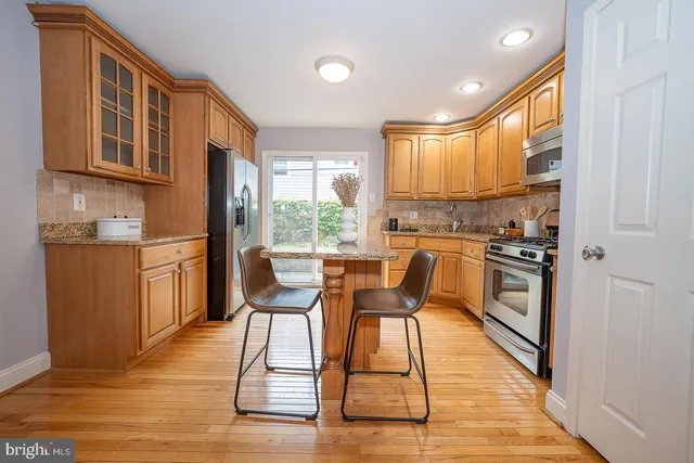 a kitchen with stainless steel appliances granite countertop a stove a sink dishwasher a microwave oven with a dining table and chairs with wooden floor