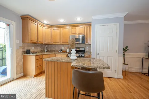 a kitchen with stainless steel appliances granite countertop a stove a sink dishwasher and a refrigerator with wooden floor