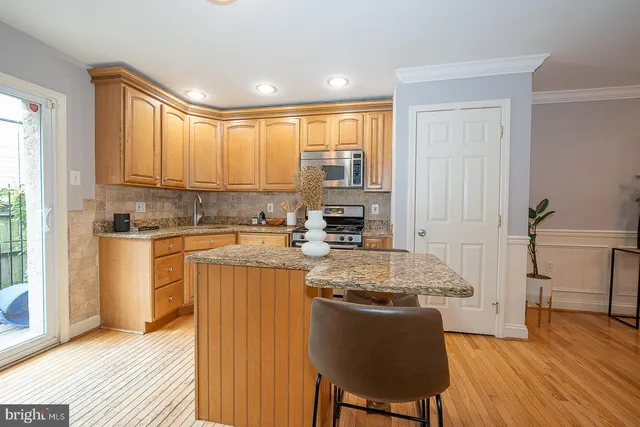 a kitchen with stainless steel appliances granite countertop a stove a sink dishwasher and a refrigerator with wooden floor