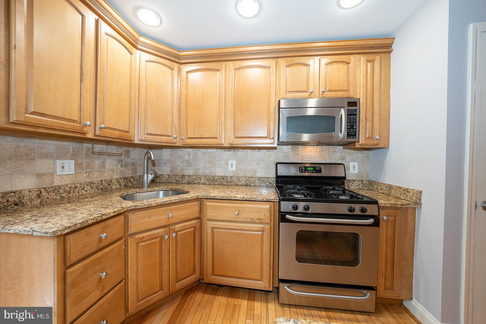 2406 Catharine Street Philadelphia, PA 19146 - Photo 8 of 37 a kitchen with granite countertop a stove a sink and a microwave