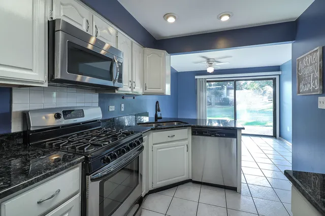 a kitchen with stainless steel appliances granite countertop a stove a sink and a microwave