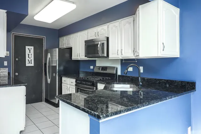 a kitchen with stainless steel appliances granite countertop a sink a stove and refrigerator