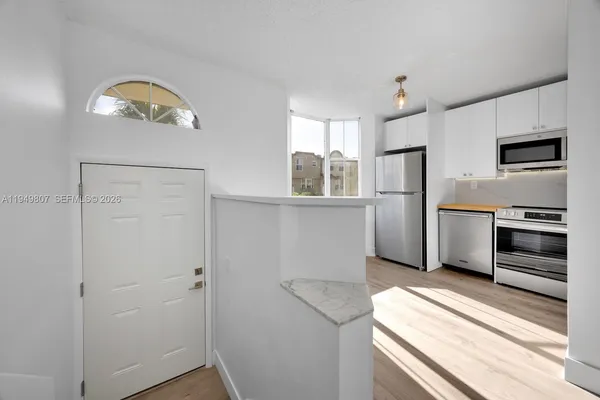 a kitchen with stainless steel appliances granite countertop a refrigerator a stove and a sink with wooden floor