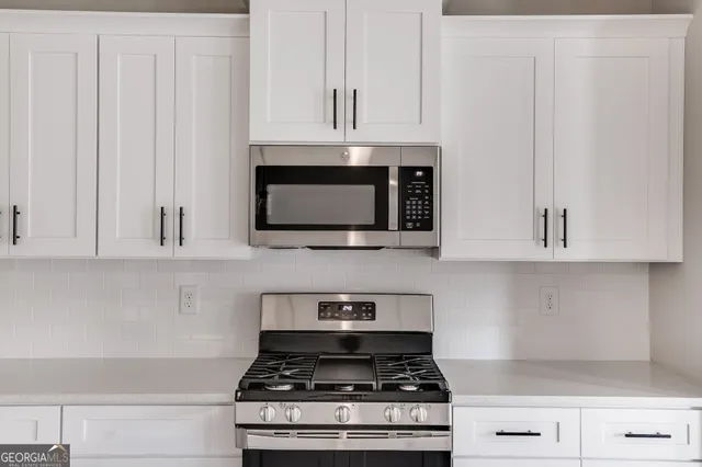 a kitchen with stainless steel appliances granite countertop white cabinets and a stove top oven