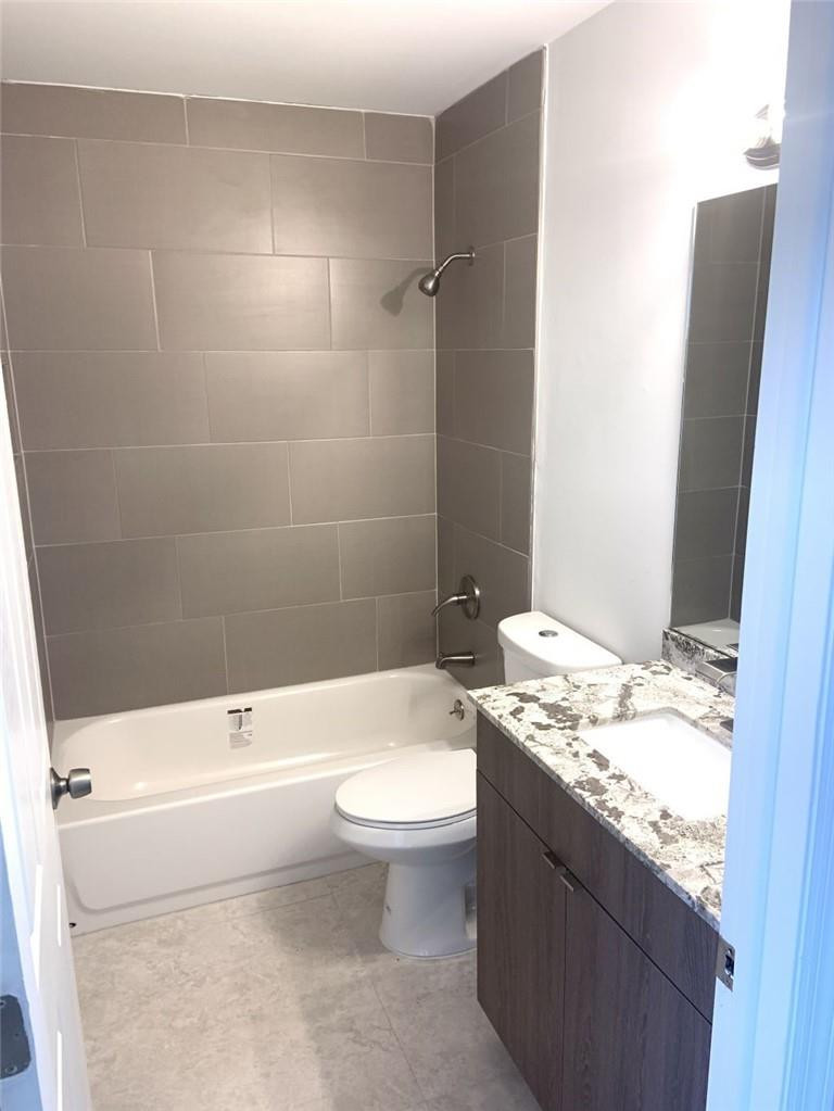 13402 Southwest 153rd Street, Unit 1901 Miami, FL 33177 - Photo 16 of 17 a bathroom with a granite countertop toilet a sink and bathtub
