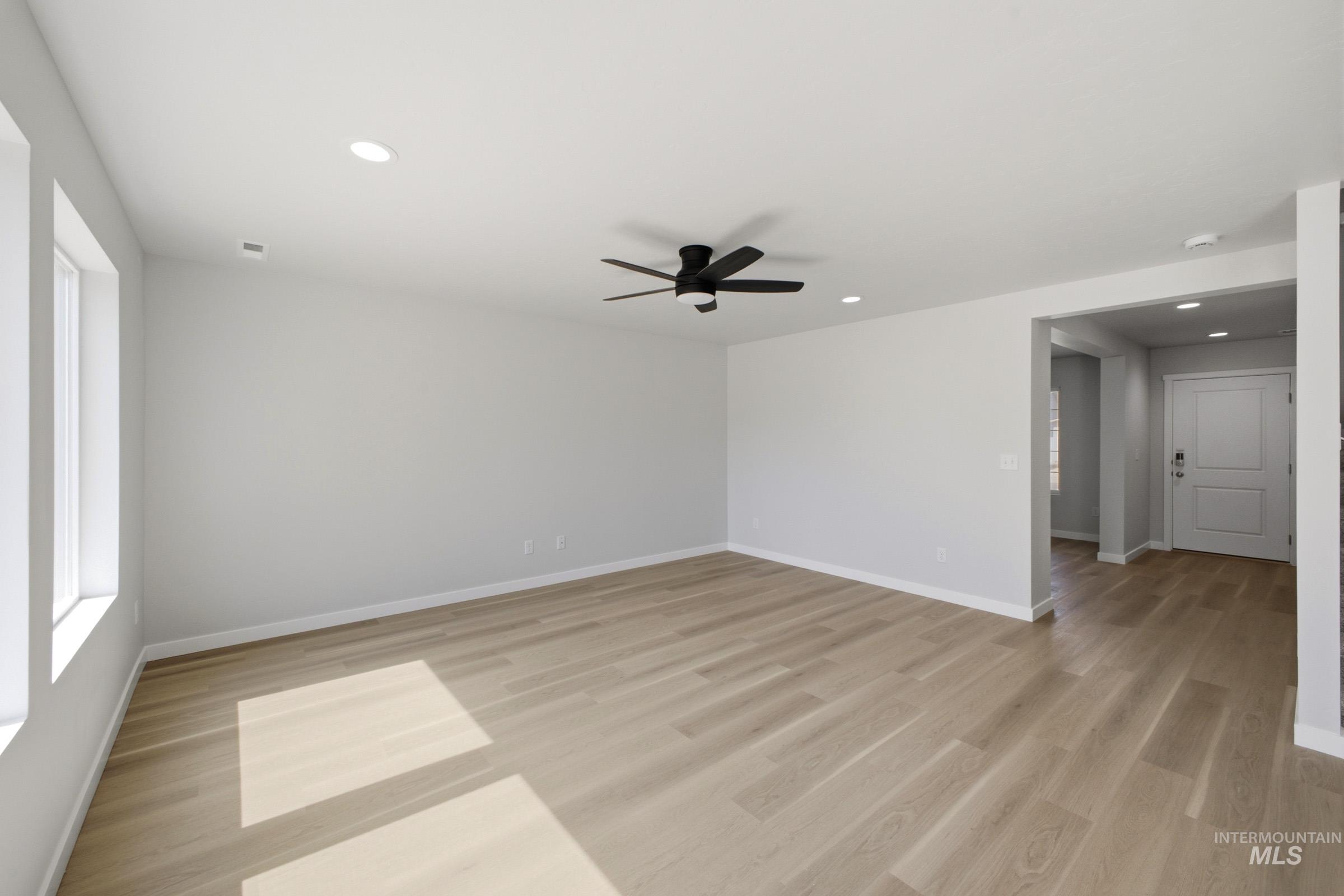 13336 Bank Street Caldwell, ID 83607 - Photo 5 of 24 Recessed lighting, light wood-finish flooring, ceiling fan, white paneled door, and multiple windows