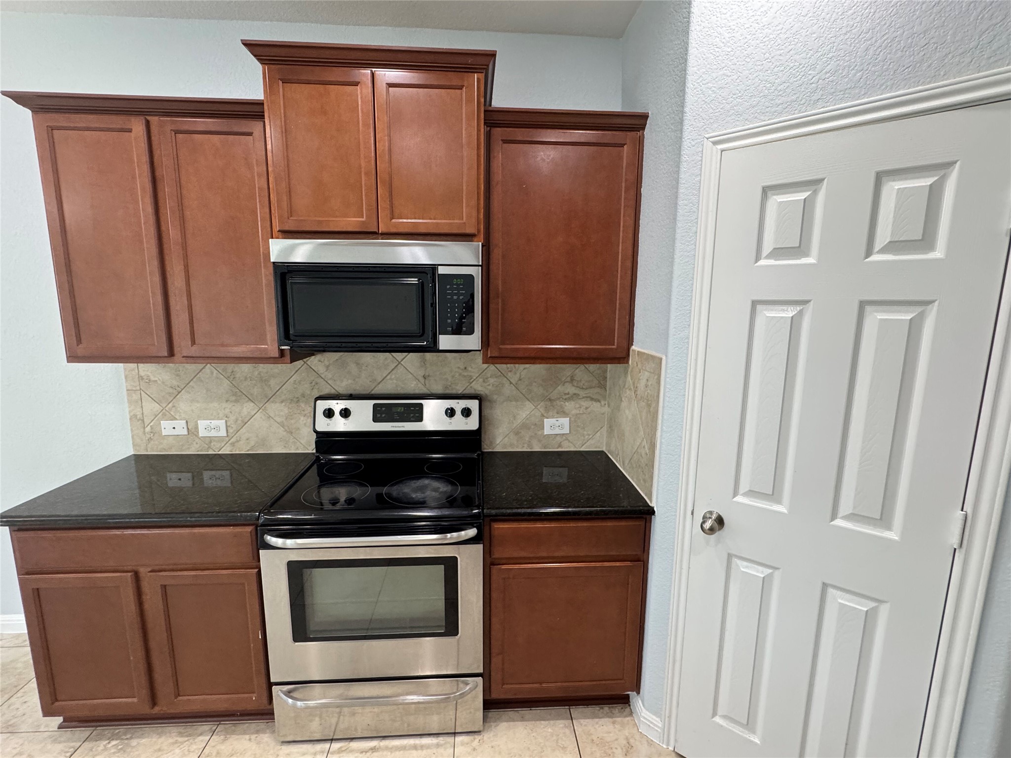 1520 Portchester Castle Path Pflugerville, TX 78660 - Photo 6 of 26 Well-equipped kitchen features dark granite counters, warm wood cabinetry, and stainless steel appliances.
