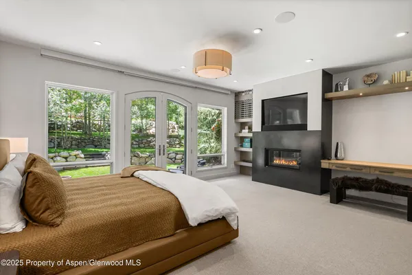 a bedroom with a bed flat screen tv and windows