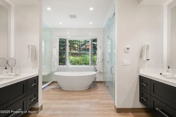 a spacious bathroom with a double vanity sink a large mirror and bathtub