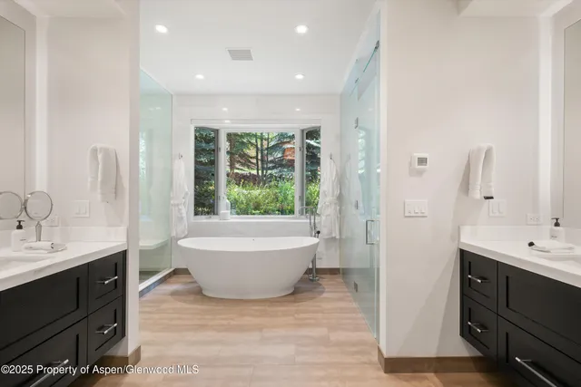 a spacious bathroom with a double vanity sink a large mirror and bathtub